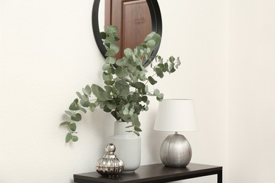 Modern console table with stylish decor and mirror on white wall in room. Interior design
