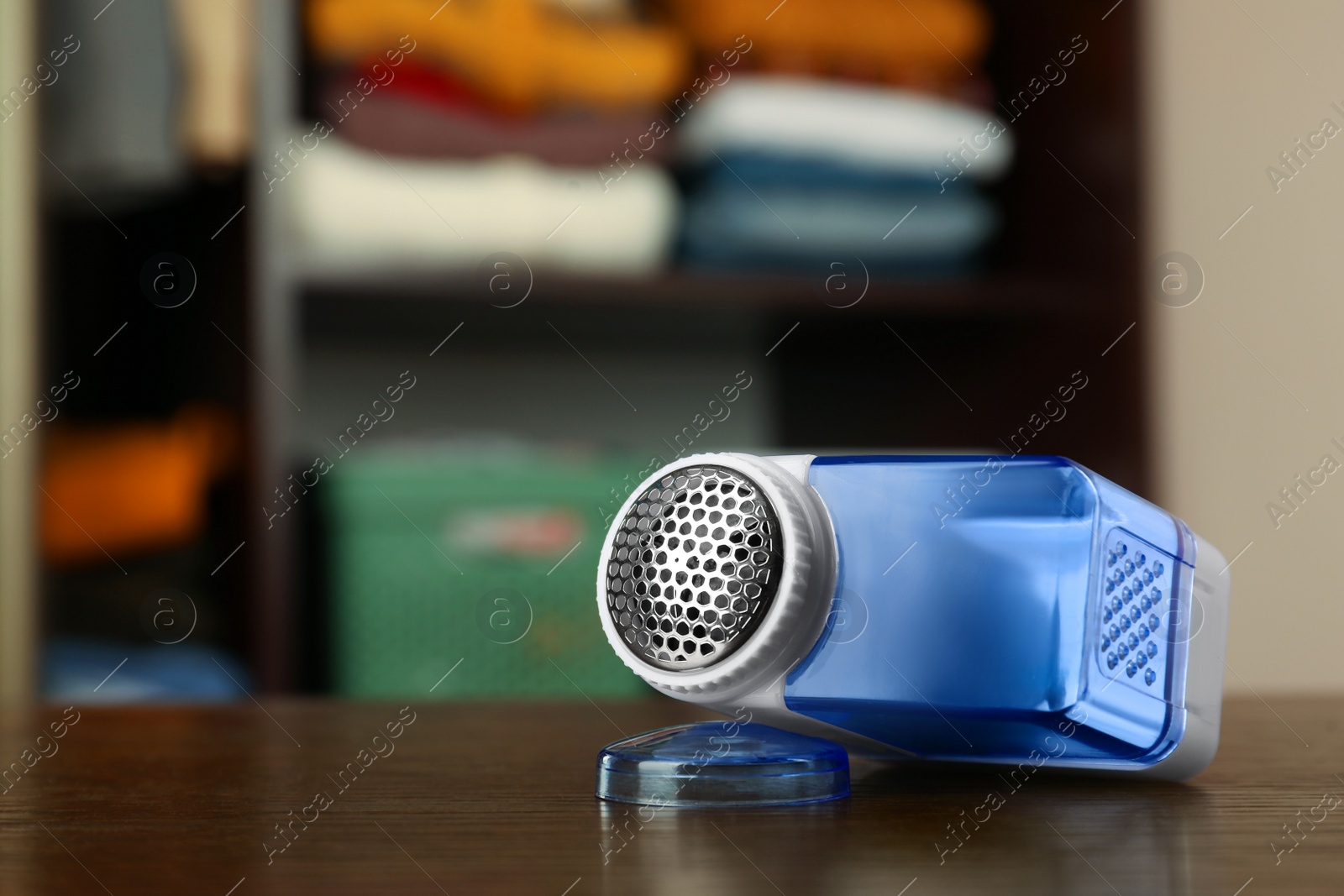 Photo of Modern fabric shaver on wooden table indoors, space for text