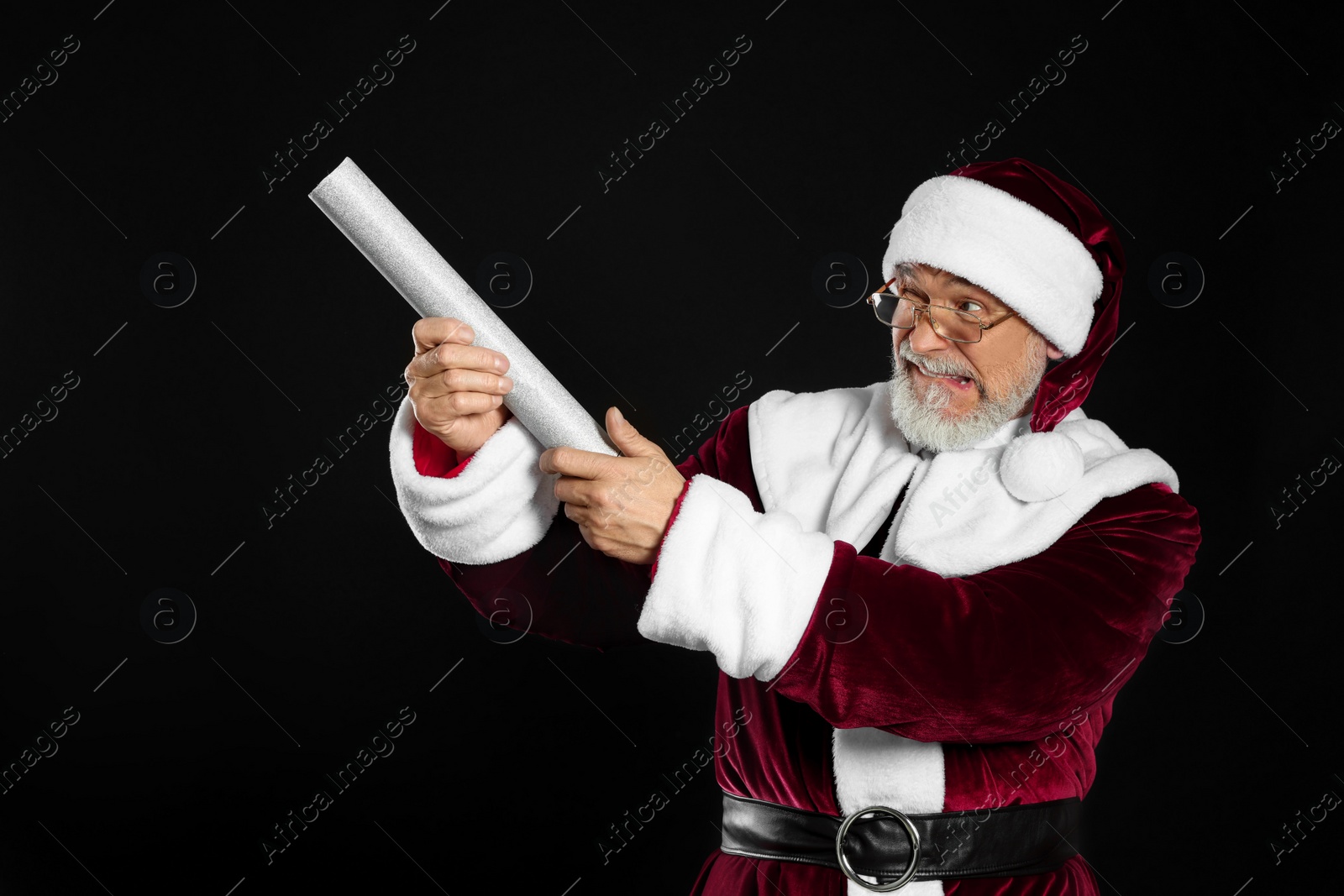 Photo of Emotional man in Santa Claus costume with party popper on black background