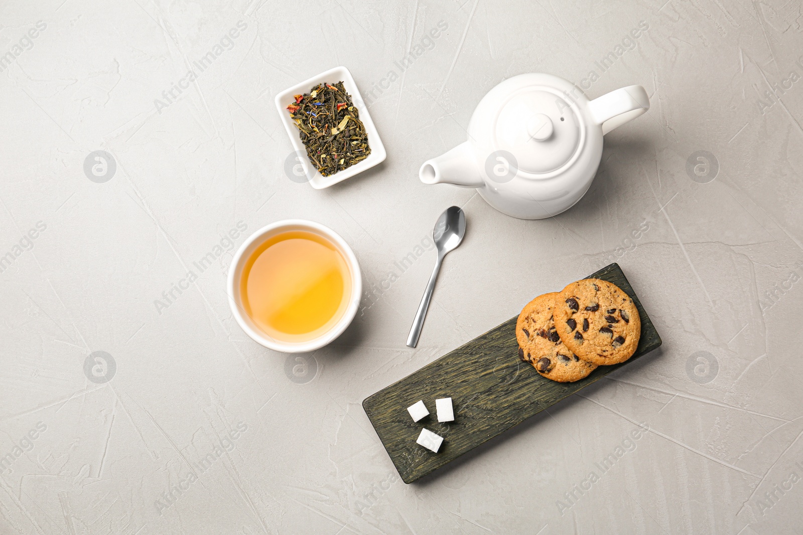 Photo of Flat lay composition with cup of hot aromatic tea and cookies on light grey table