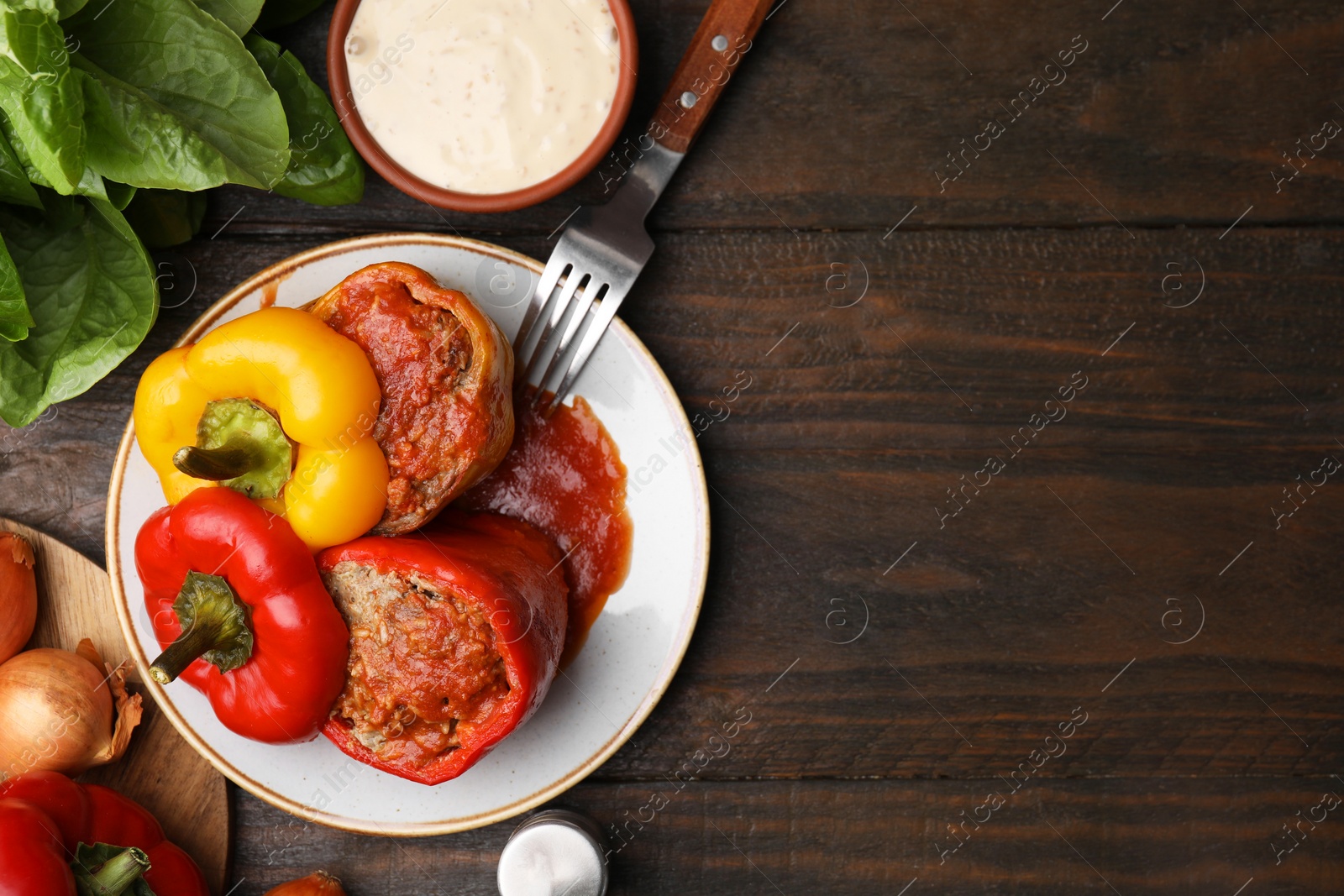 Photo of Delicious stuffed bell peppers served on wooden table, flat lay. Space for text