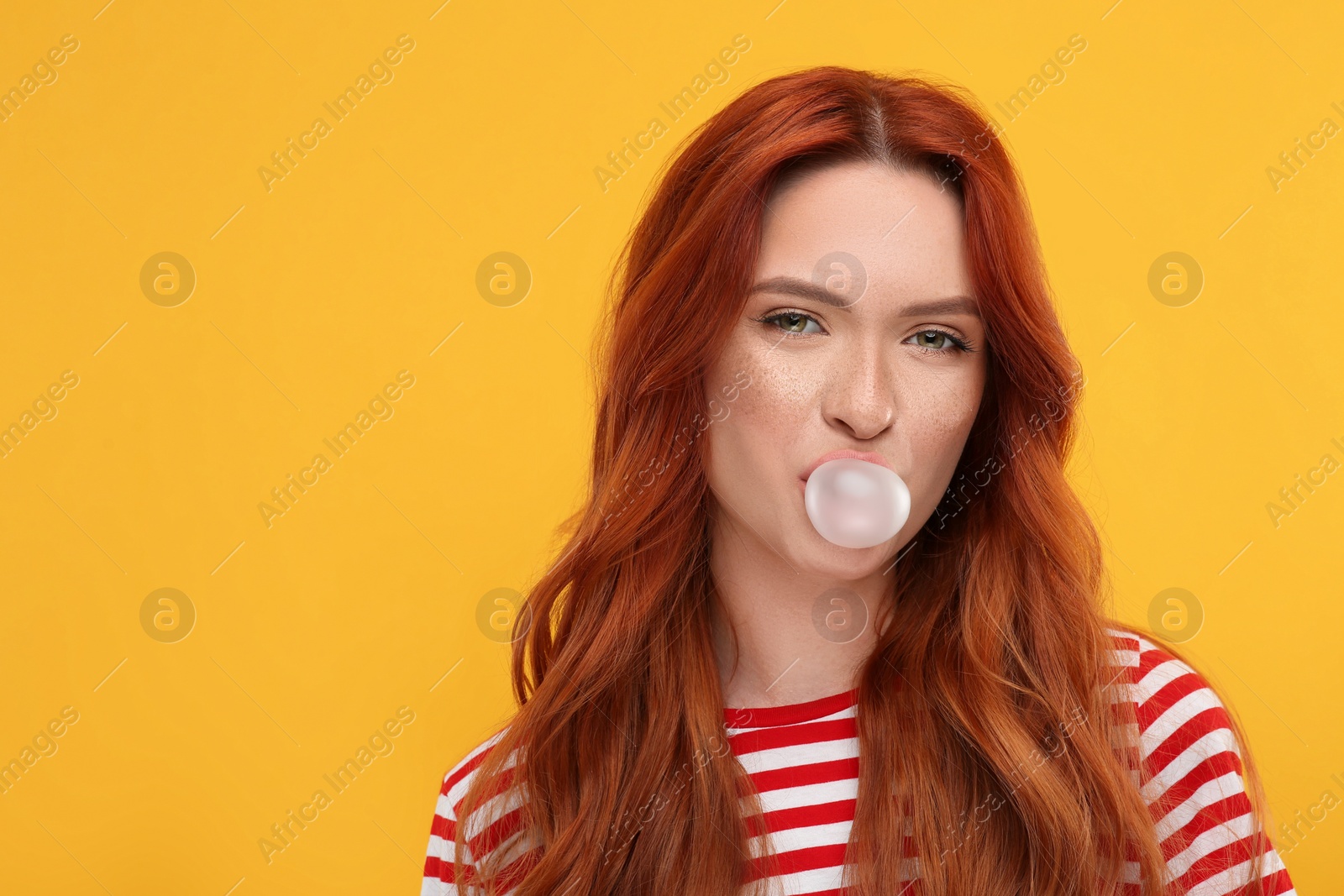 Photo of Portrait of beautiful woman blowing bubble gum on orange background. Space for text