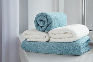 Photo of Stack of fresh soft towels on windowsill