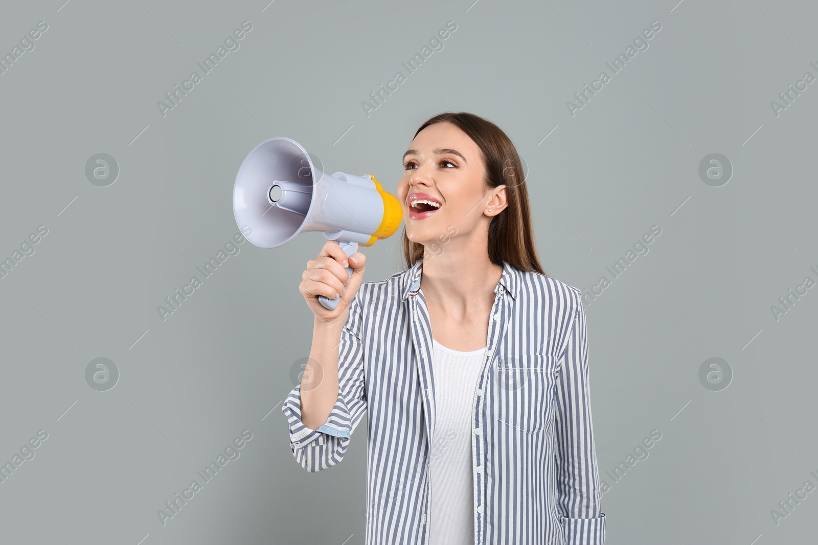 Photo of Young woman with megaphone on light grey background