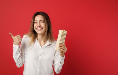 Young woman with delicious shawarma on red background, space for text