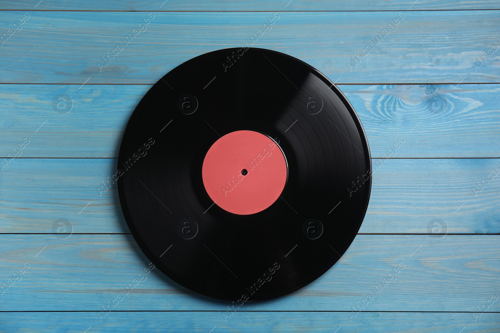 Photo of Vintage vinyl record on blue wooden background, top view