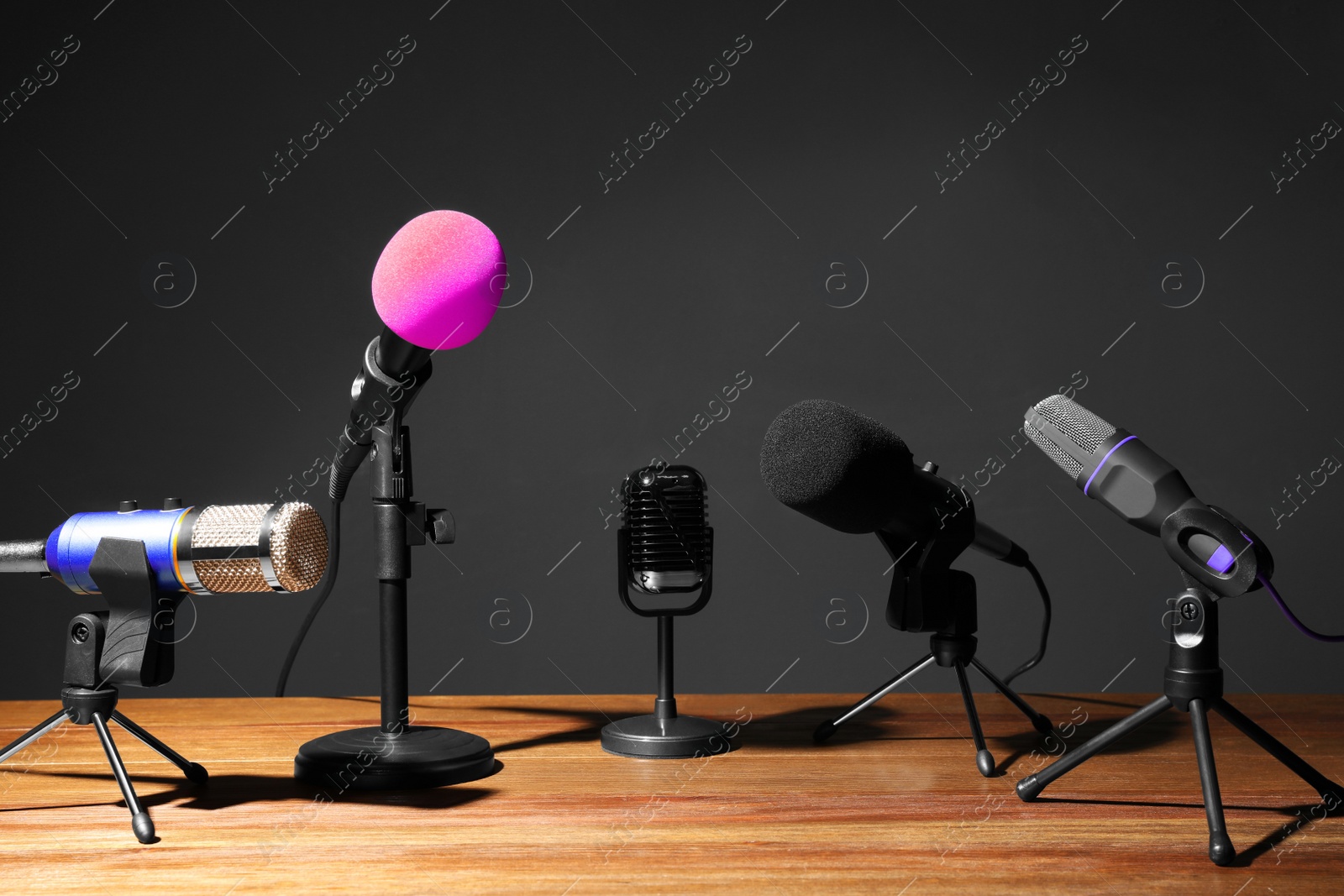 Photo of Set of different microphones on wooden table. Journalist's equipment