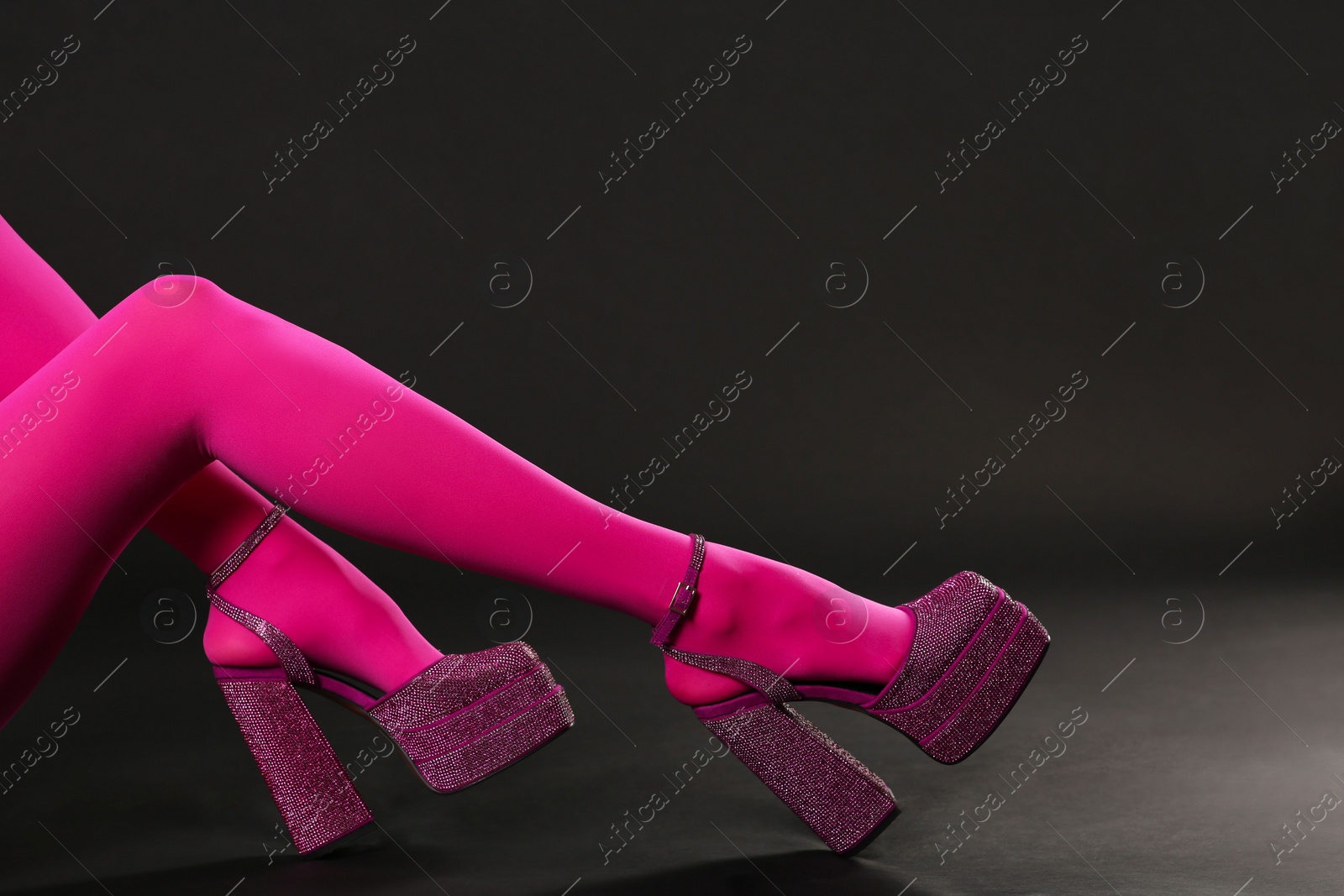 Photo of Woman wearing pink tights and high heeled shoes with platform and square toes on black background, closeup. Space for text