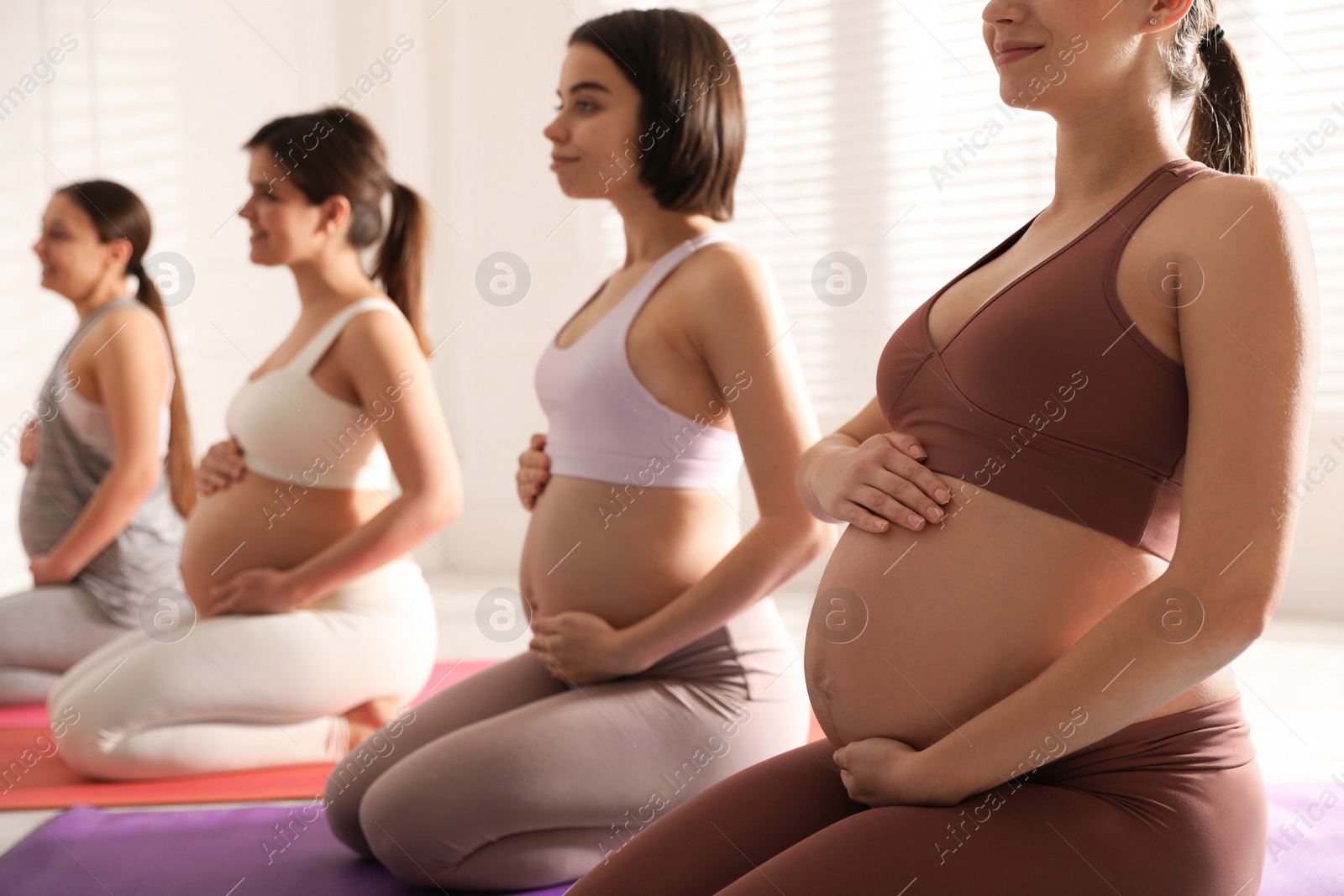 Photo of Group of pregnant women practicing yoga in gym, closeup