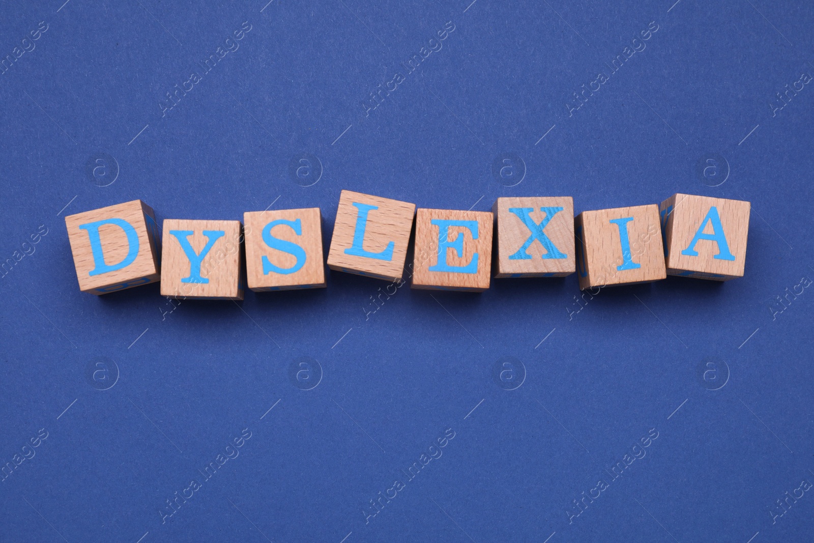 Photo of Wooden cubes with word Dyslexia on blue background, flat lay
