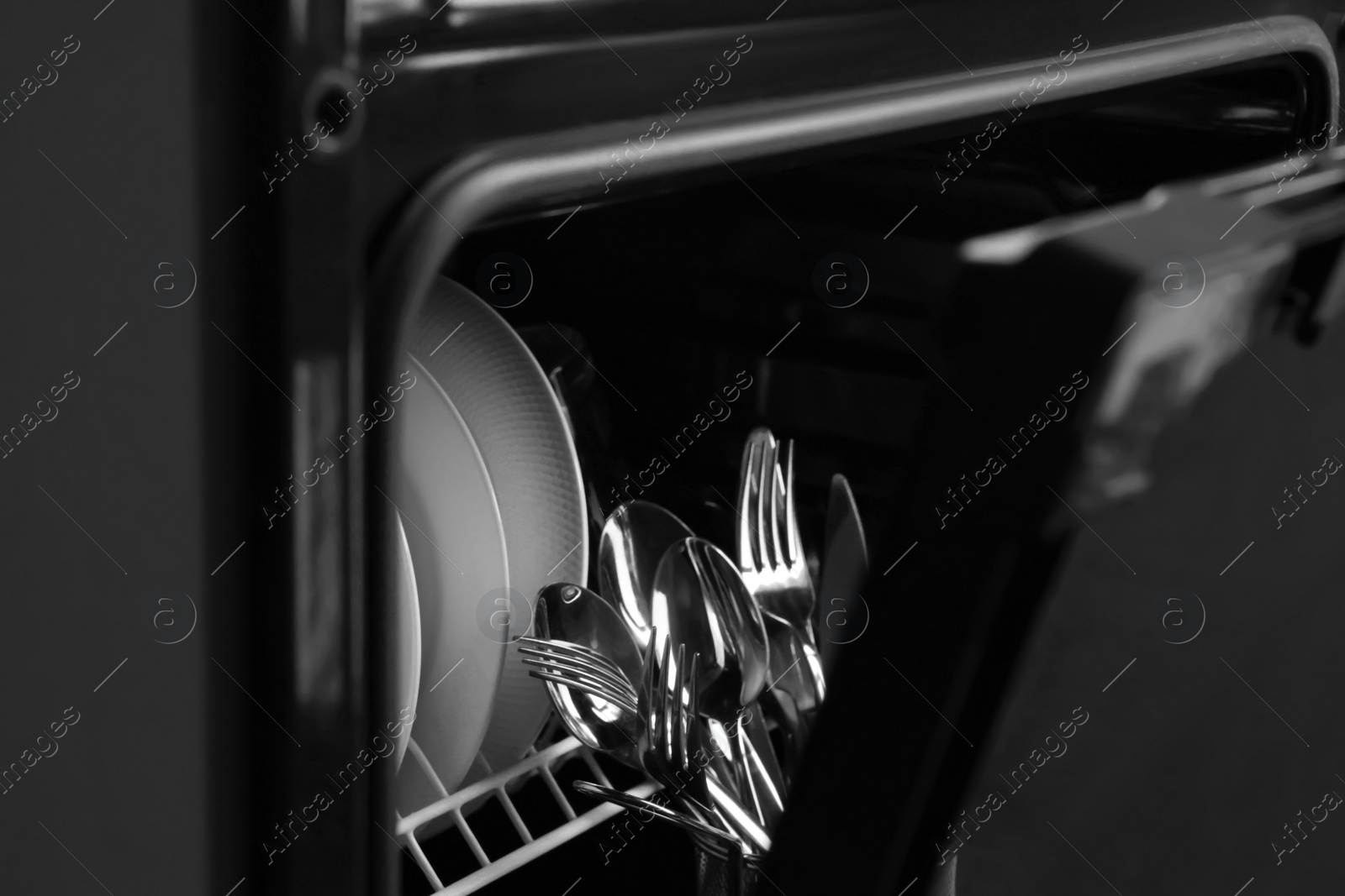 Photo of Clean plates and cutlery in dishwasher, closeup