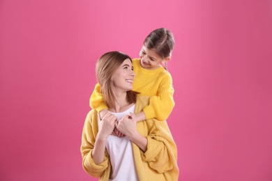Happy woman and daughter in stylish clothes on color background