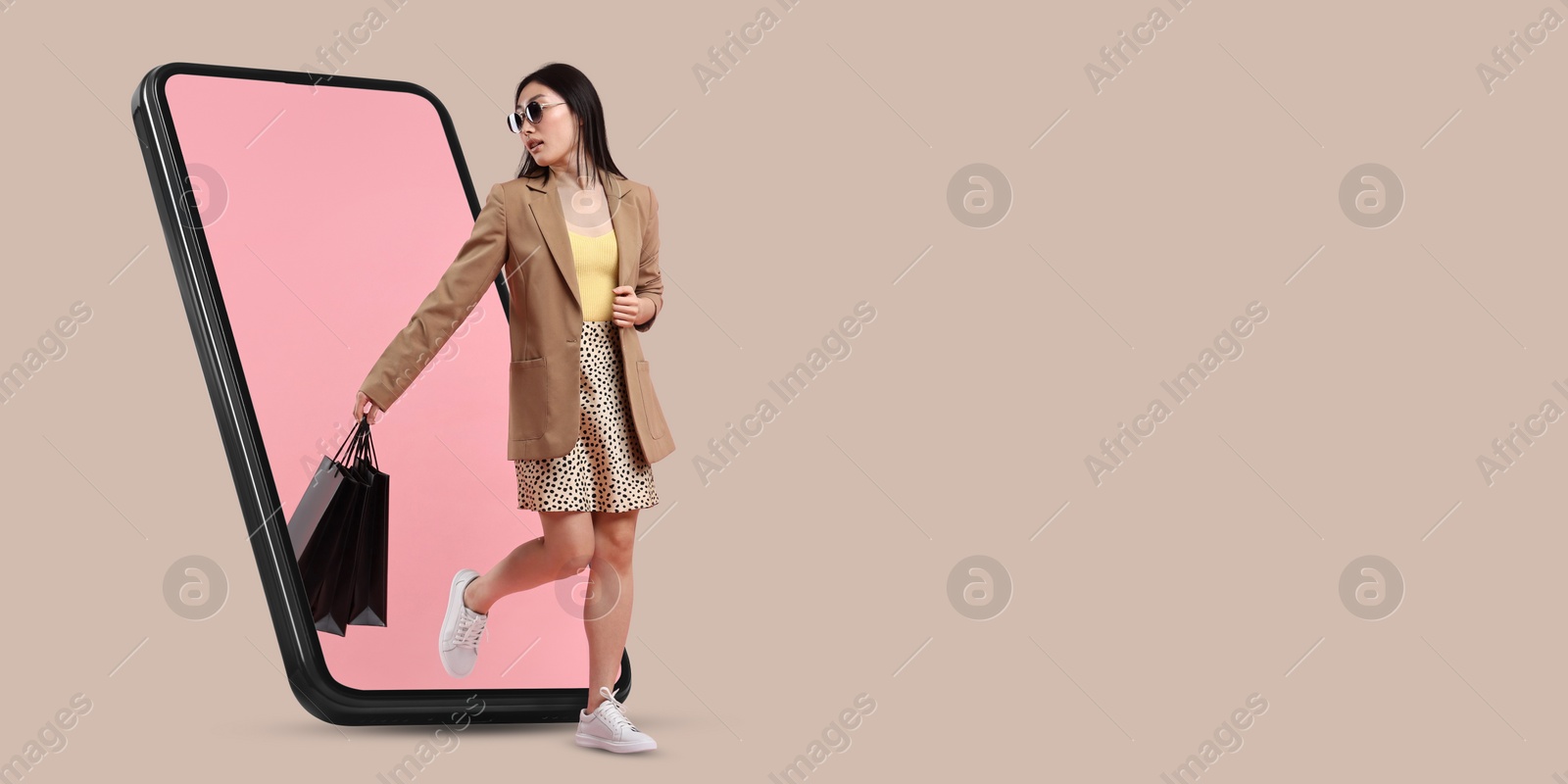 Image of Online shopping. Woman with paper bags walking out from smartphone on beige background, space for text. Banner design