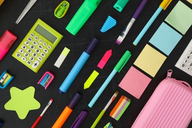 Flat lay composition with different school stationery on blackboard. Back to school