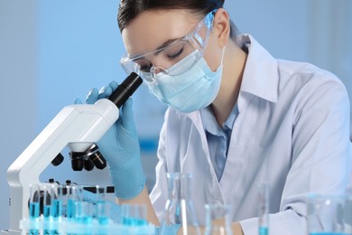 Scientist working with microscope and test tubes in laboratory