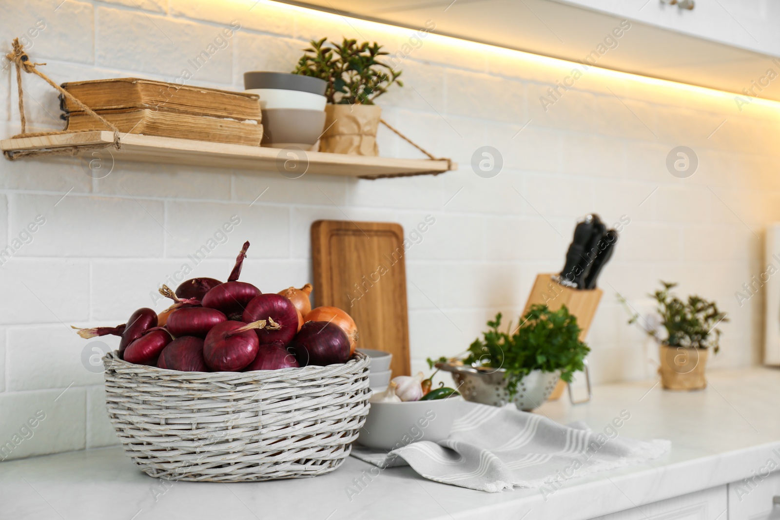 Photo of Fresh onions on white countertop in modern kitchen