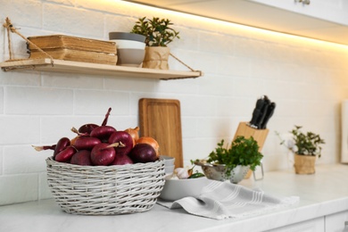 Photo of Fresh onions on white countertop in modern kitchen
