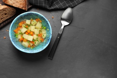 Photo of Bowl of fresh homemade vegetable soup served on black table, flat lay. Space for text