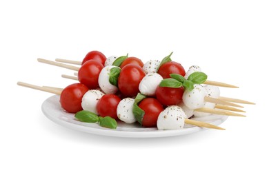 Photo of Plate of Caprese skewers with tomatoes, mozzarella balls, basil and spices isolated on white