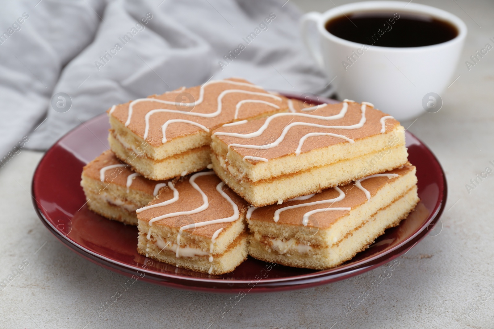 Photo of Tasty sponge cakes and hot drink on light grey table