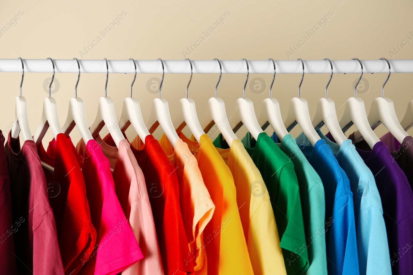 Photo of Many t-shirts hanging in order of rainbow colors, closeup