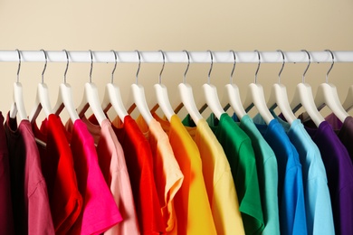 Photo of Many t-shirts hanging in order of rainbow colors, closeup