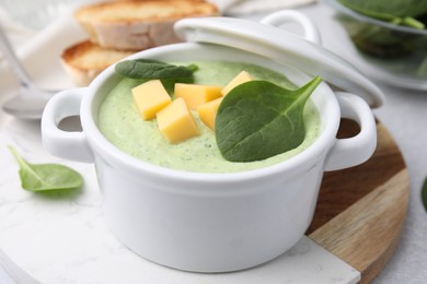 Photo of Delicious spinach cream soup with cheese in bowl on light grey table, closeup