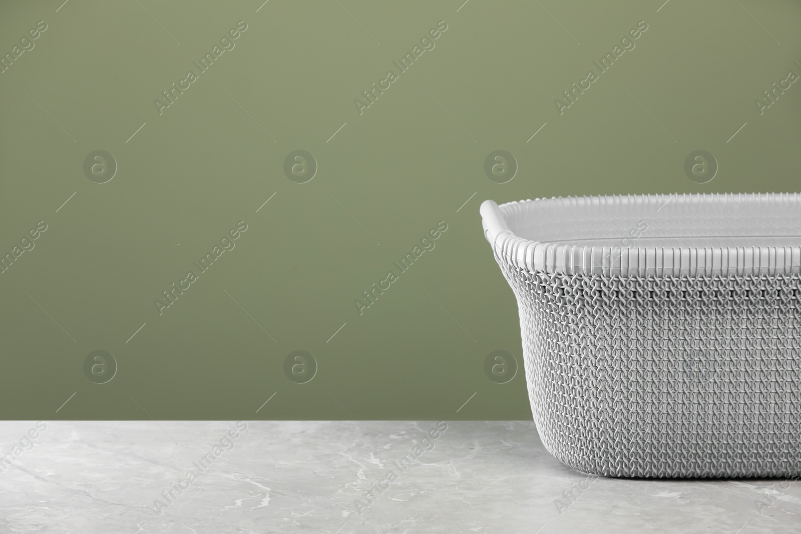 Photo of Empty plastic laundry basket near light green wall. Space for text