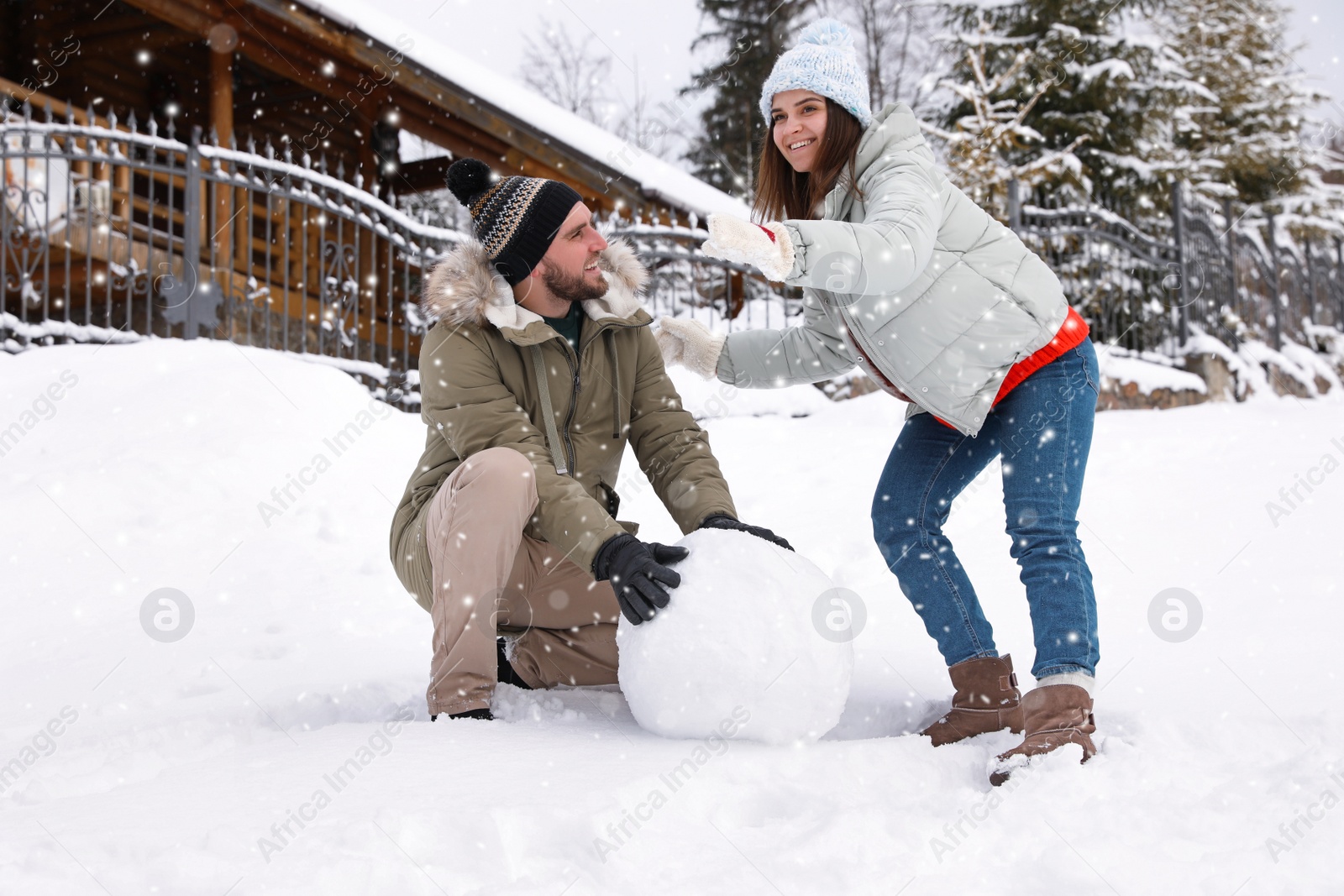Photo of Happy couple making ball for snowman outdoors. Winter vacation