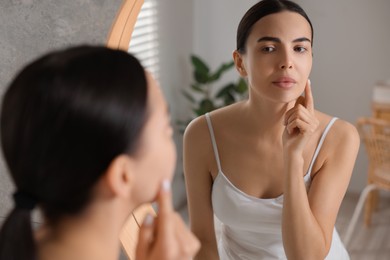 Woman with dry skin looking at mirror in bathroom