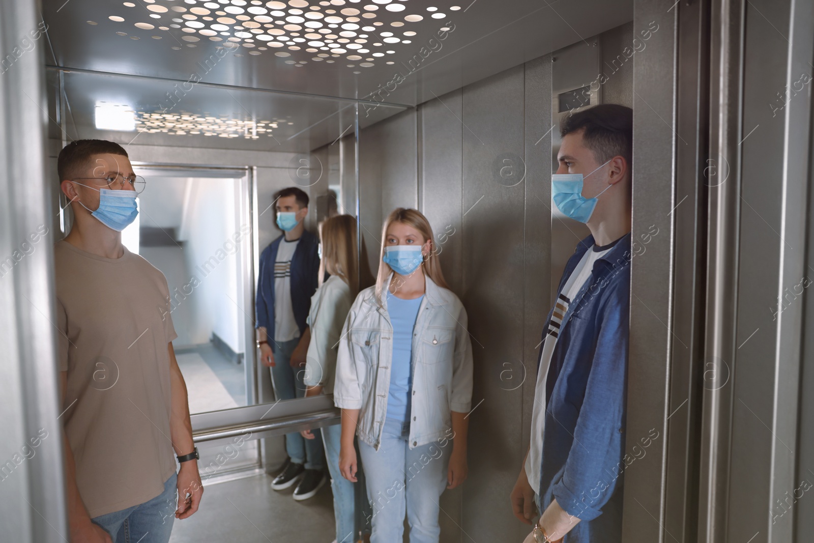 Photo of Group of people with face masks in elevator. Protective measure