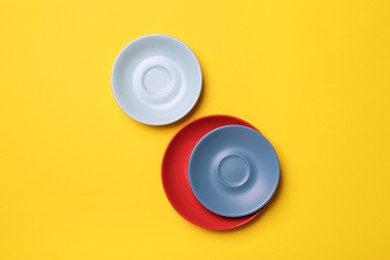 Photo of Clean ceramic plates on yellow background, flat lay