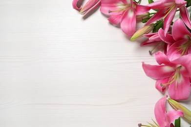 Photo of Beautiful pink lily flowers on white wooden table, space for text