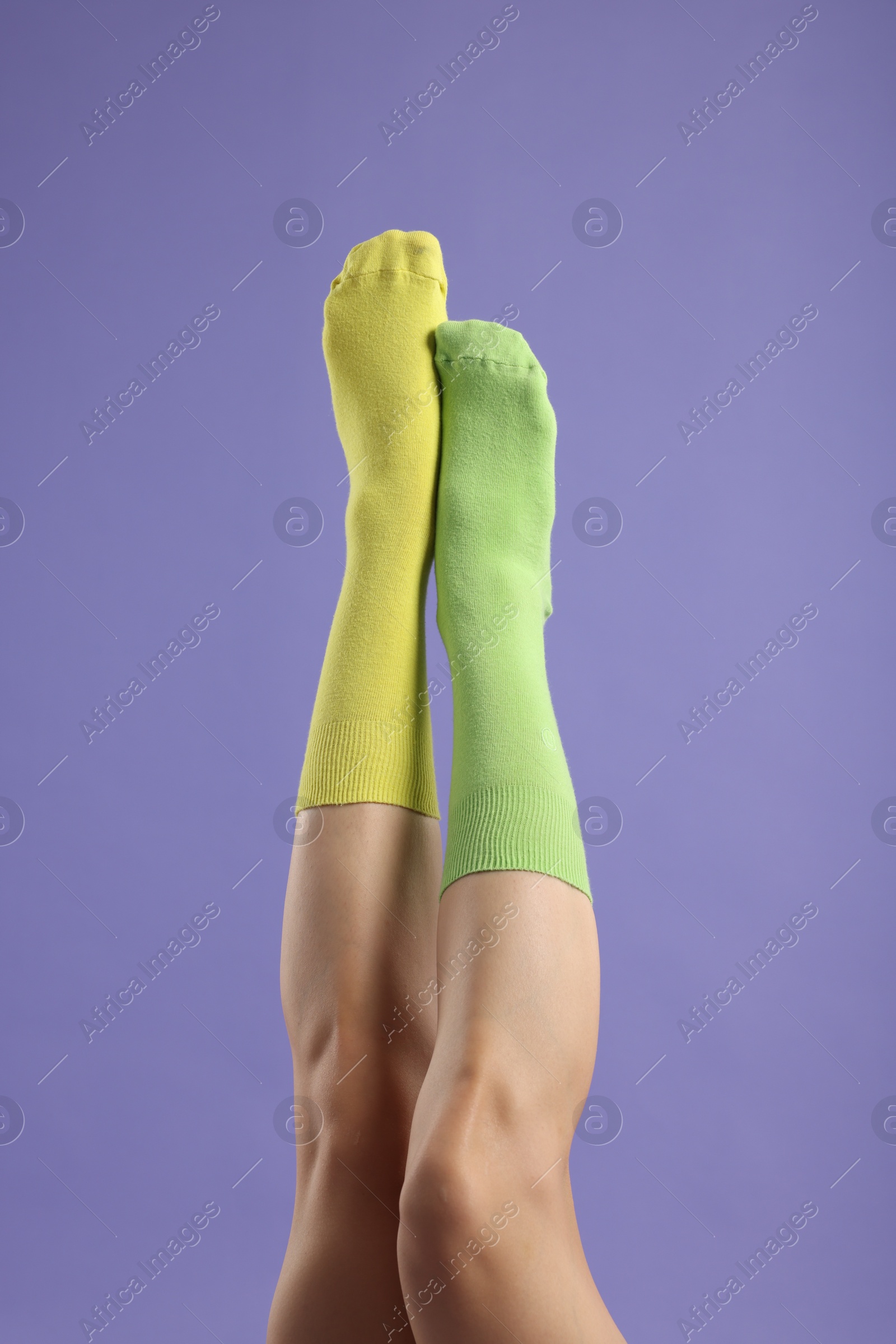 Photo of Woman in different stylish socks on violet background, closeup