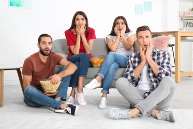 Photo of Young friends watching TV in living room
