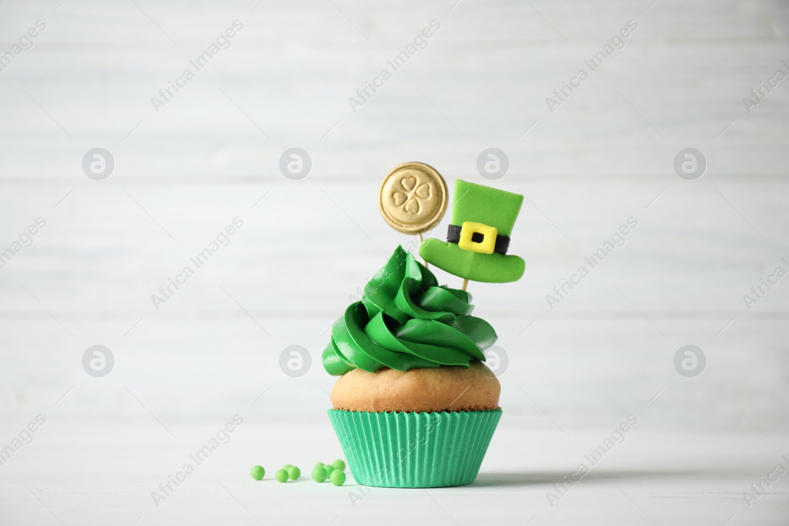 Photo of Decorated cupcake on white wooden table. St. Patrick's Day celebration