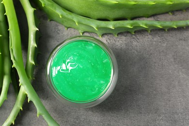 Photo of Bowl with natural gel and aloe vera leaves on grey table, flat lay