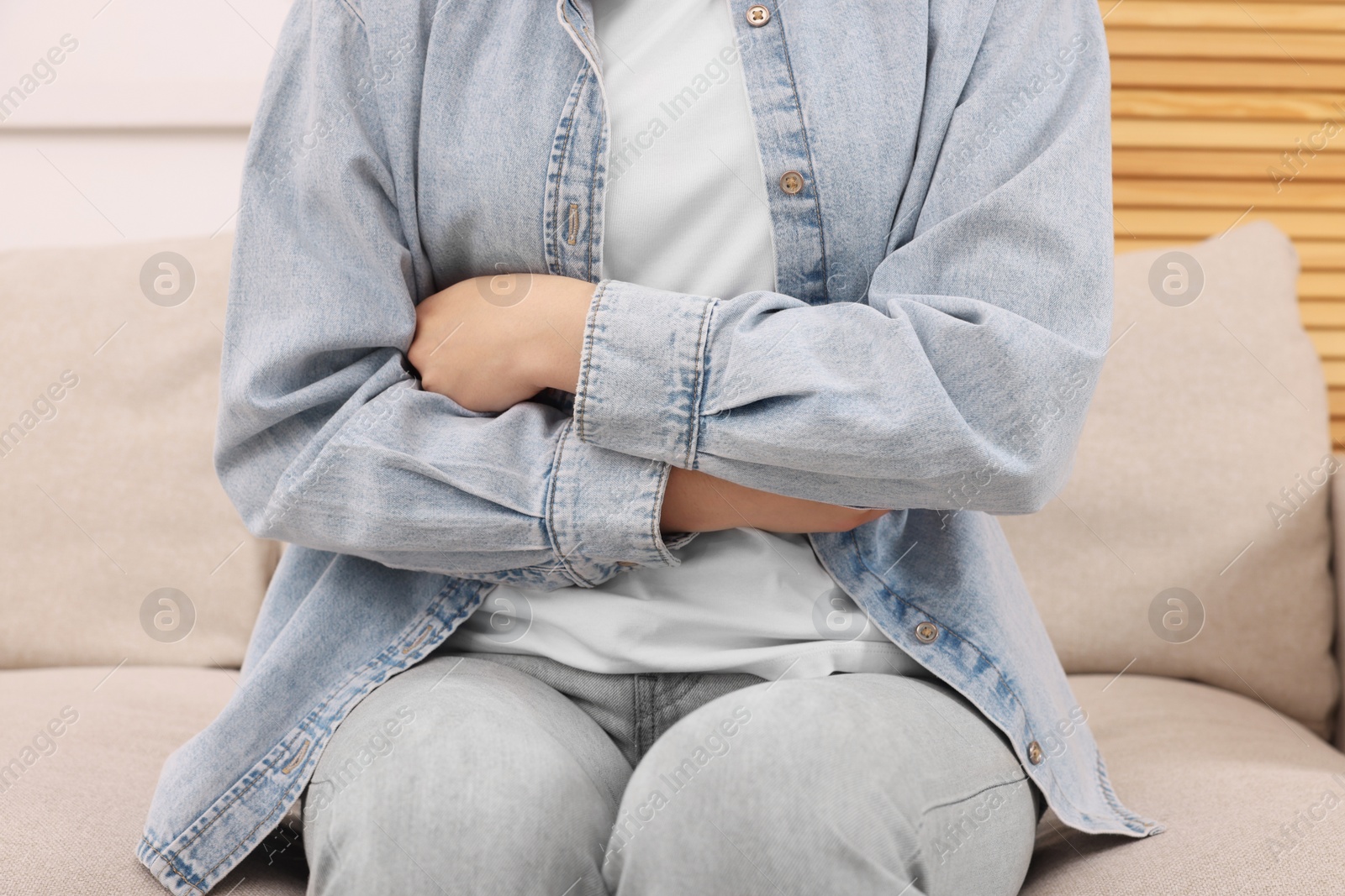 Photo of Young woman suffering from stomach pain indoors, closeup