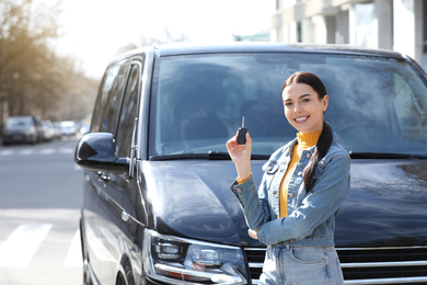 Photo of Young woman with key near car on city street. Buying new auto