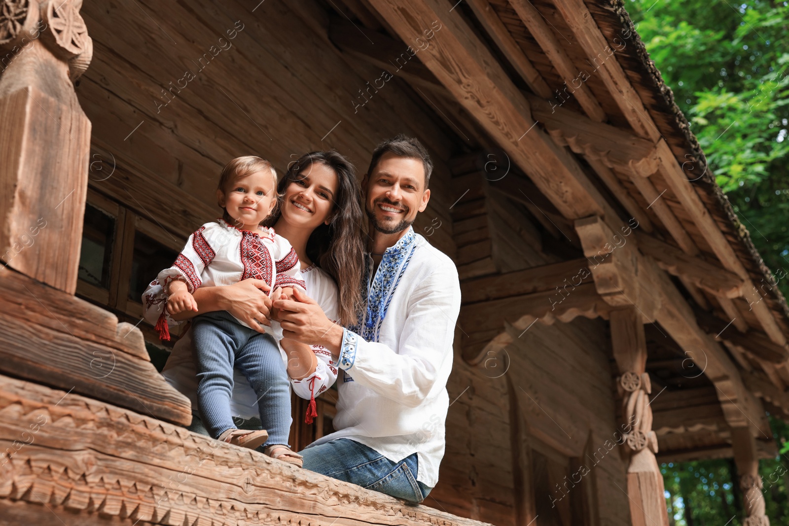 Photo of Happy family in Ukrainian national clothes on wooden terrace