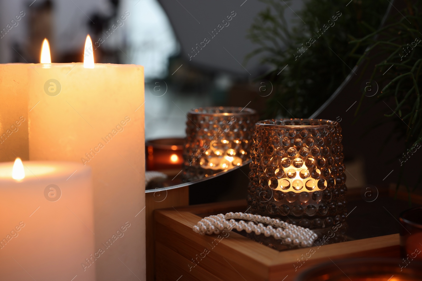 Photo of Lit candles on wooden dressing table indoors