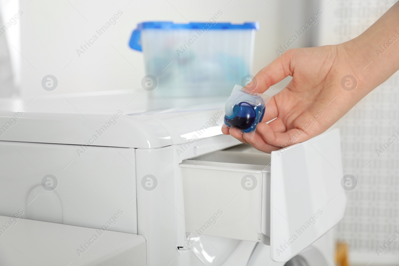 Photo of Woman putting laundry detergent capsule into washing machine, closeup