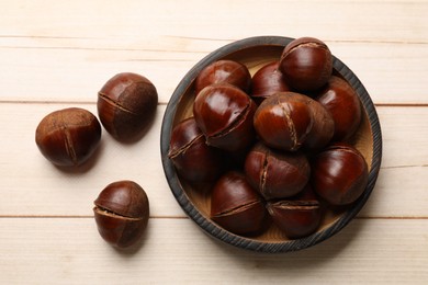 Roasted edible sweet chestnuts on wooden table, flat lay