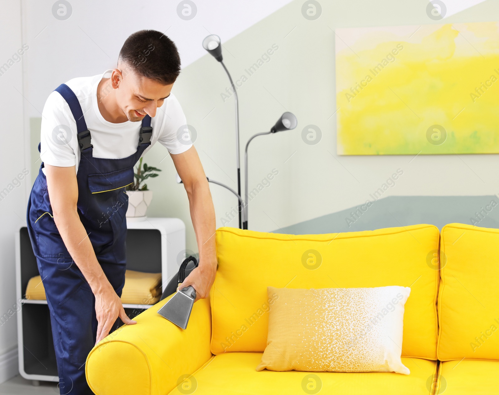 Photo of Dry cleaning worker removing dirt from sofa indoors