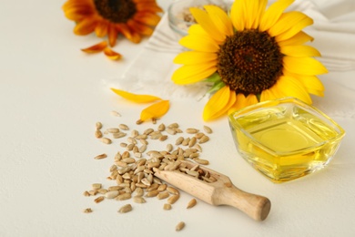 Photo of Sunflower oil in glass bowl and seeds on white table