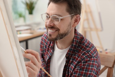 Photo of Man painting on canvas in studio. Creative hobby