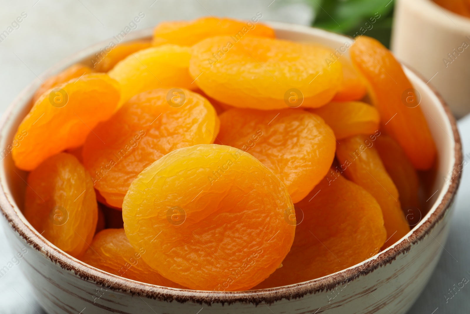 Photo of Bowl of tasty apricots on table, closeup. Dried fruits