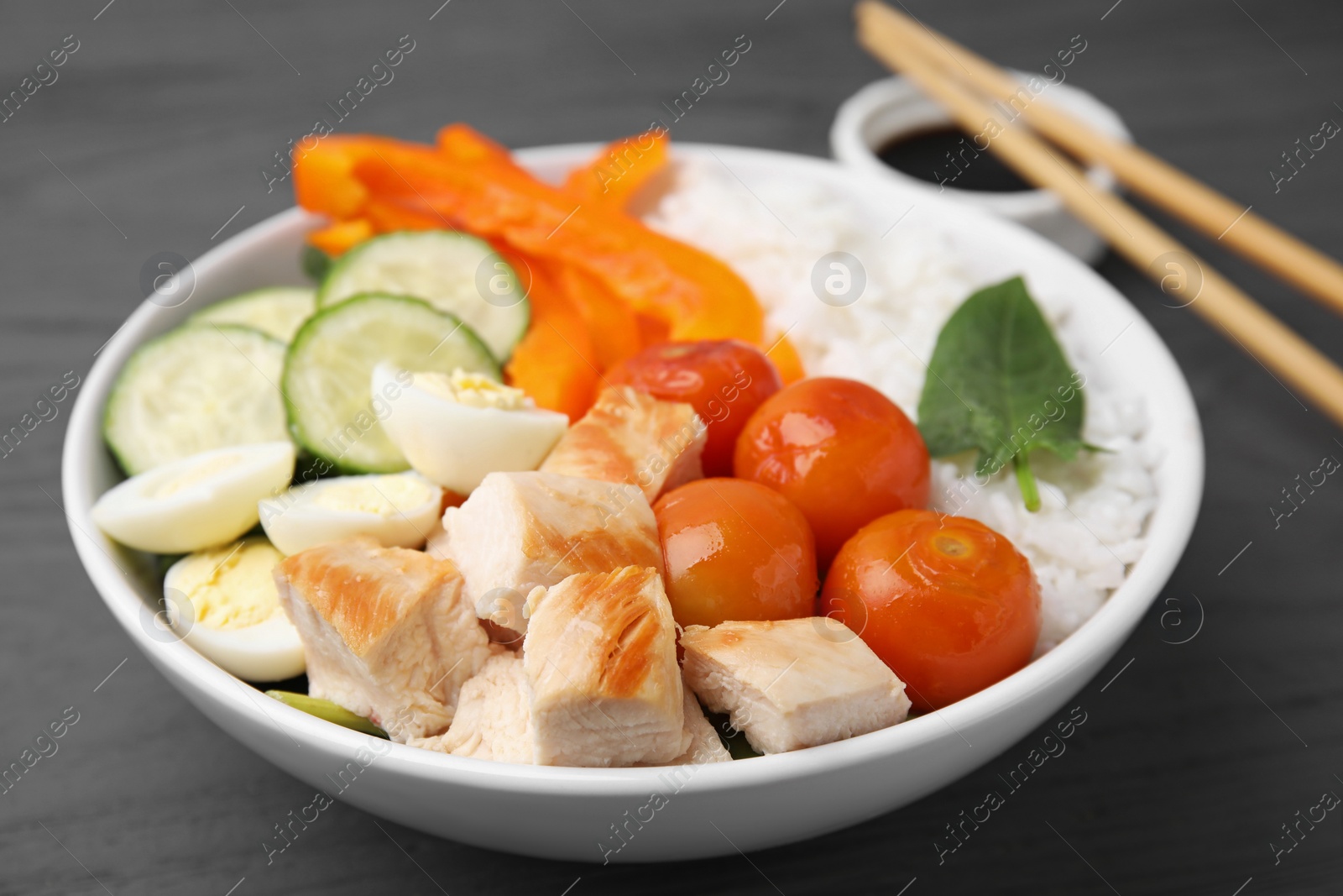 Photo of Delicious poke bowl with meat, rice, eggs and vegetables on wooden table, closeup