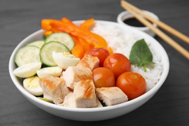 Photo of Delicious poke bowl with meat, rice, eggs and vegetables on wooden table, closeup