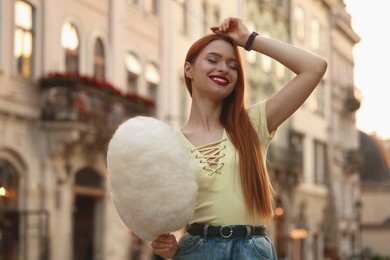 Smiling woman posing with cotton candy on city street